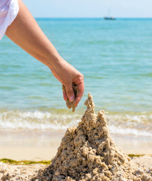 istock hand builds a from the wet sea sand 1040474144