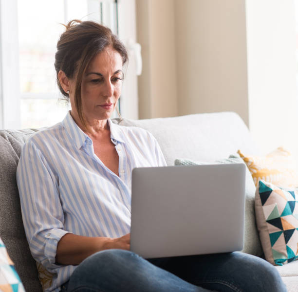 istock Middle aged woman using laptop in the sofa with a confident expression on smart face thinking serious 1040480856