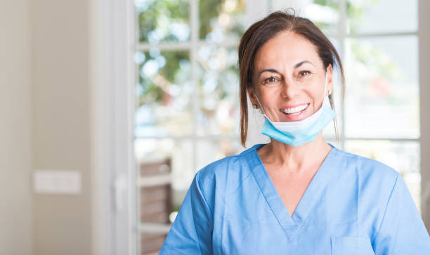 donna medico di mezza età con un viso felice in piedi e sorridente con un sorriso sicuro che mostra i denti - toothy smile relaxation white healthcare and medicine foto e immagini stock