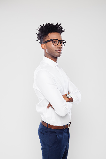 Portrait of african businessman standing with and attitude on white background. African man in formal wear wearing eyeglasses looking away with his arms crossed.