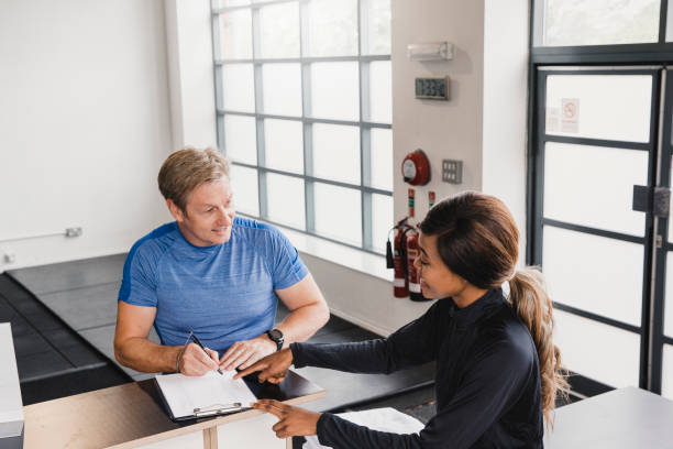 Mature Gym Goer Signing Up For Personal Training Sessions