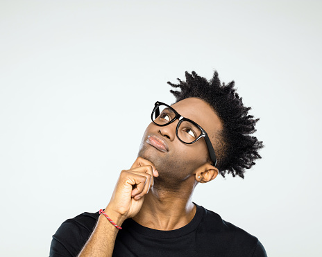 Close up portrait of pensive young afro american man wearing nerdy glasses looking up at copy space on white background