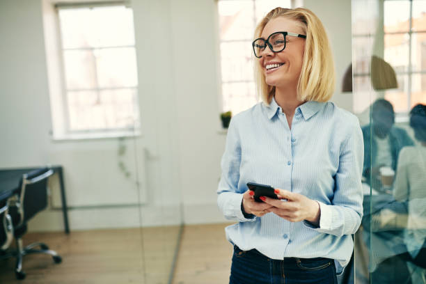 istock Laughing young businesswoman standing with her cellphone at work 1040494994