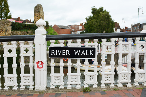 River Walk sign on ornamental railings featuring Invicta, alongside the River Medway Tonbridge, Kent. Norman castle ruins can been seen in the background.