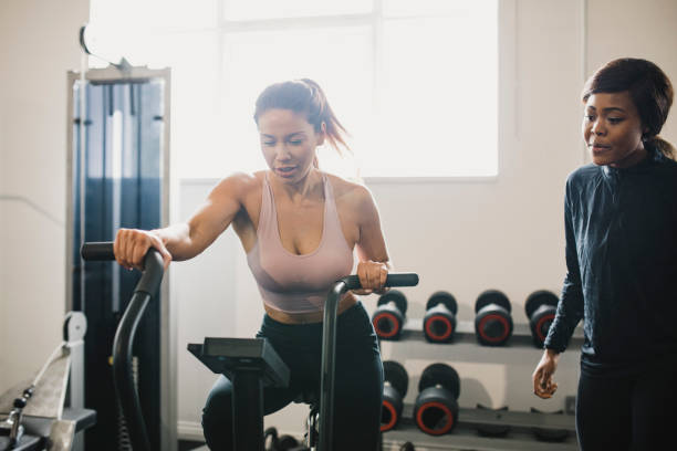 istock Woman on Exercise Bike with Personal Trainer 1040504678