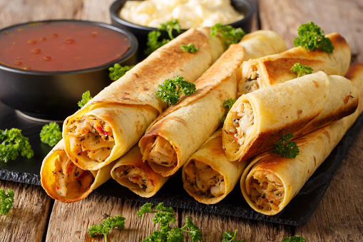 Baked taquitos with chicken and cheese close-up on the table. horizontal
