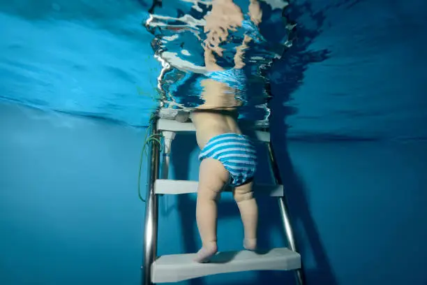 The baby down the stairs into the pool. The view from under the water. Horizontal orientation