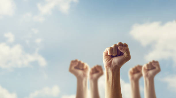 Peoples raised fist air fighting and sunlight effect, Competition, teamwork concept.