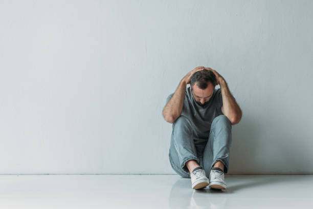 istock full length view of scared depressed man sitting with hands behind head on floor 1040530516