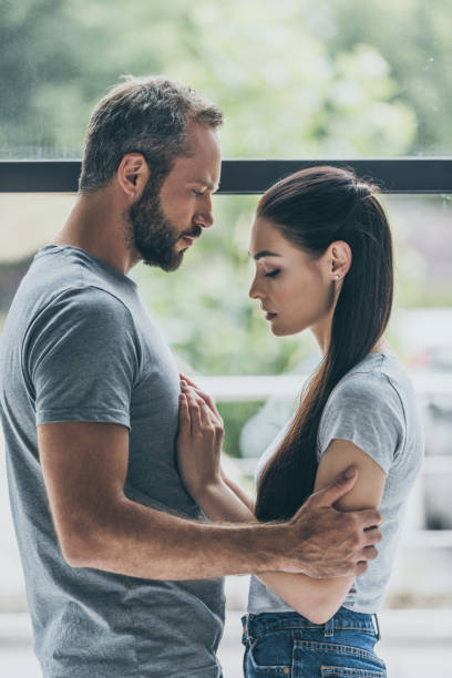 istock side view of bearded man embracing sad young girlfriend while standing together near window 1040530742