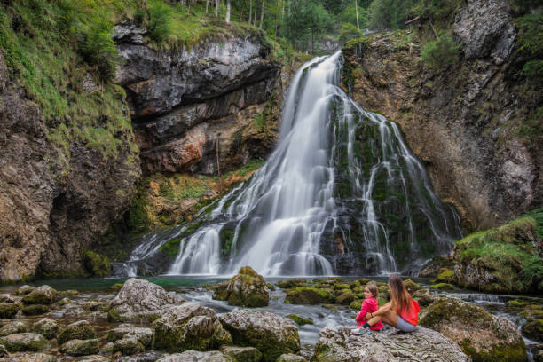 Mother and daughter are sitting at the gollinger waterfall in salzburger land and enjoy the time