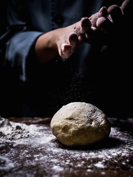 istock pastry chef hand sprinkling white flour over Raw Dough on kitchen table. 1040532590