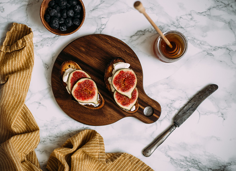 Grill Toast with Honey, Cream Cheese or Ricotta and Fresh Ripe Figs on Cutting Board.