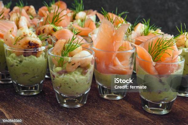 Cold Buffet With Appetizers In Glasses Prawn Shrimps And Salmon On Avocado Cream And Dill Garnish On Dark Wood Stock Photo - Download Image Now