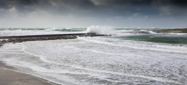 istock Furious  storm in high tide with a big dam and mole with pathway, Enez Croaz Hent, Brittany, France 1040544744