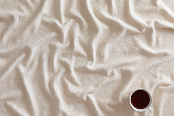 Cup of coffee or tea on beige textured background with warm plaid, copy space. Flat lay, top view