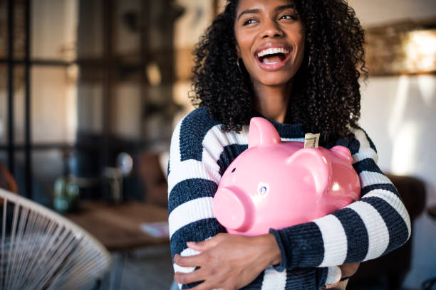Black woman hugging her piggy bank Black young woman hugging her pink piggy bank money bills and currency stock pictures, royalty-free photos & images