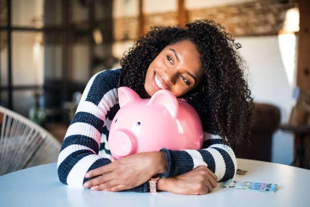 Black woman hugging her piggy bank stock photo