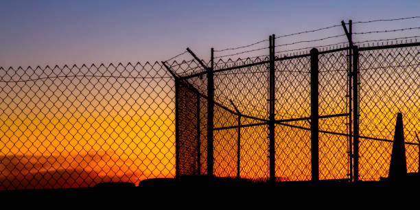 istock Mesh wire fence and barbeb wire at sunset 1040562456