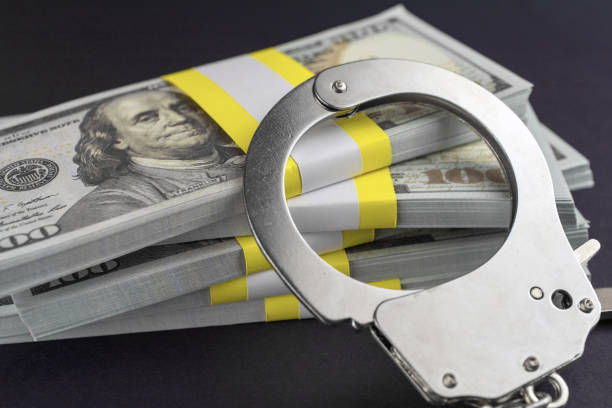 money and handcuffs. financial crime Share scams  Skimming    concept white collar crime handcuffs stock pictures, royalty-free photos & images