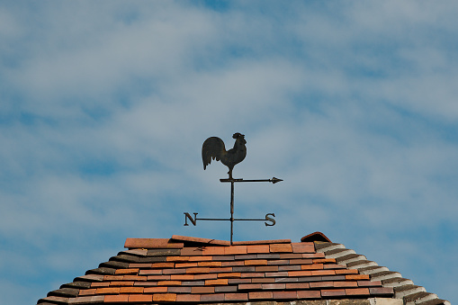 An old fashioned weather vane on top of a weather worn roof. Photographed; Wool, Dorset, UK. September 2018