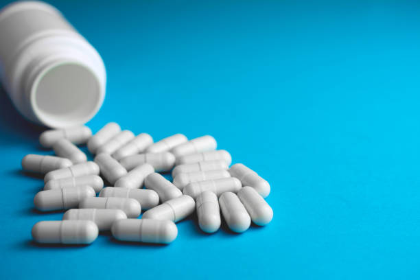 istock Pills tablets capsule plastic drugs bottle blue background. 1040567494