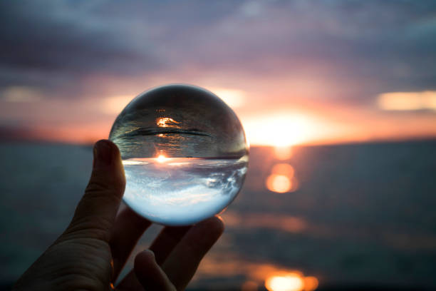 Bright Sunset with Sun on Horizon over Ocean Captured in Glass Ball stock photo