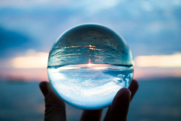 tramonto sull'orizzonte sull'oceano catturato in una sfera di vetro trasparente - water fire circle ball foto e immagini stock