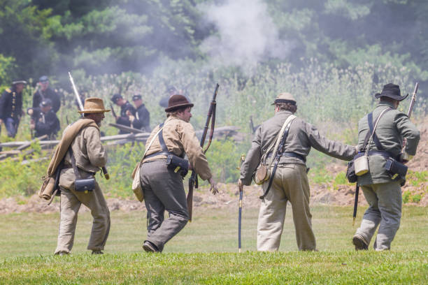 american civil war reenactment -- four confederate soldiers head for a confrontation with union troops on the left - confederate soldier imagens e fotografias de stock