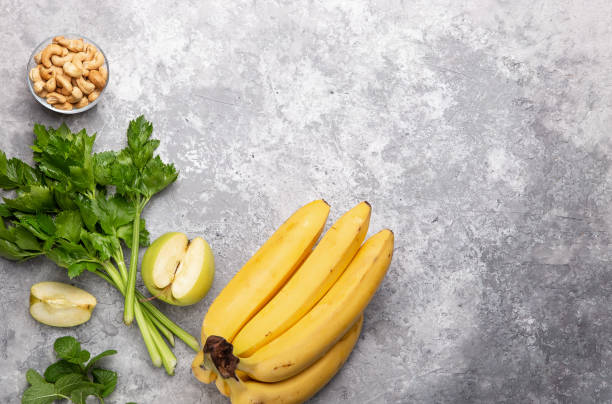 Fresh green apple, celery stalks, cashew and bananas