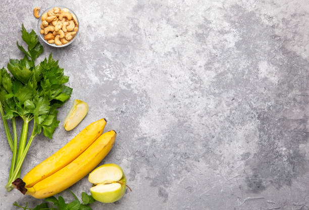 Fresh green apple, celery stalks, cashew and bananas