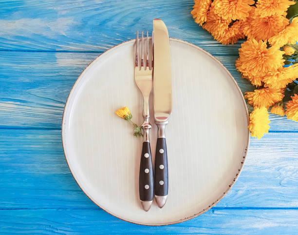 istock fork, plate, knife with yellow chrysanthemums on a blue wooden background 1040600374