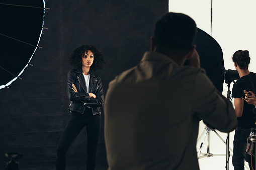 Rear view of a photographer taking photos of female model. Photographer with his team during a photo shoot.