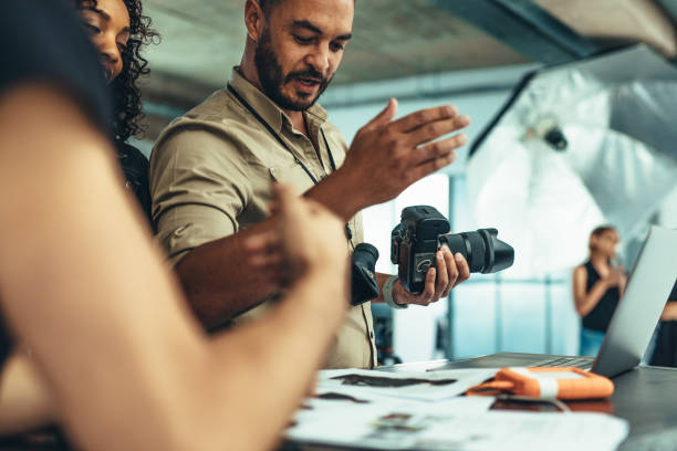 photographer having a discussion with his team - professional photographer imagens e fotografias de stock