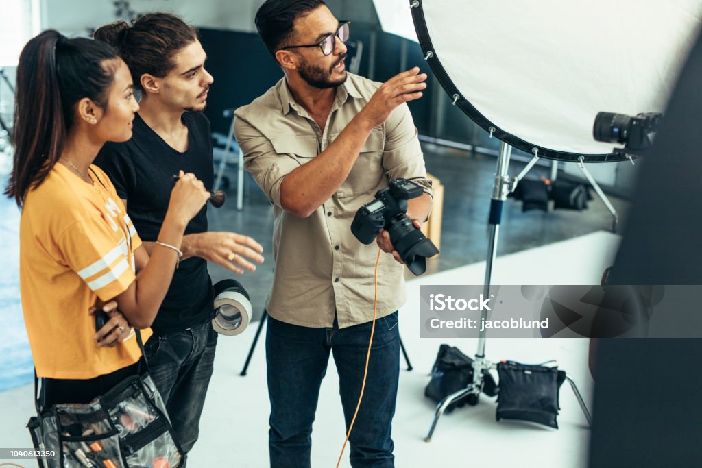 Travaillant avec son équipe pendant une séance photo dans un studio de photographe - Photo de Photographe libre de droits
