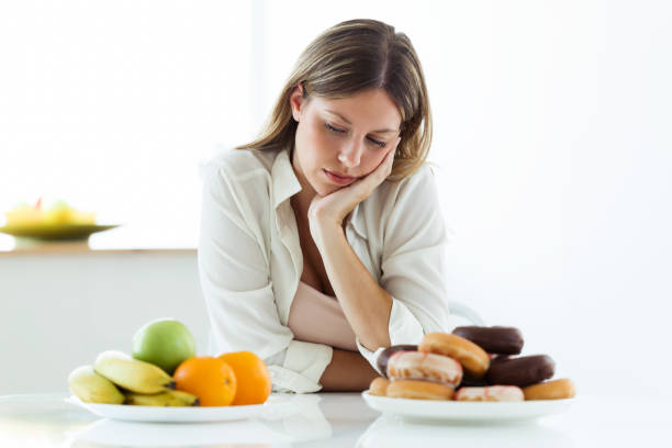 istock Sadness young woman choosing between fruit and sweet at home. 1040619096