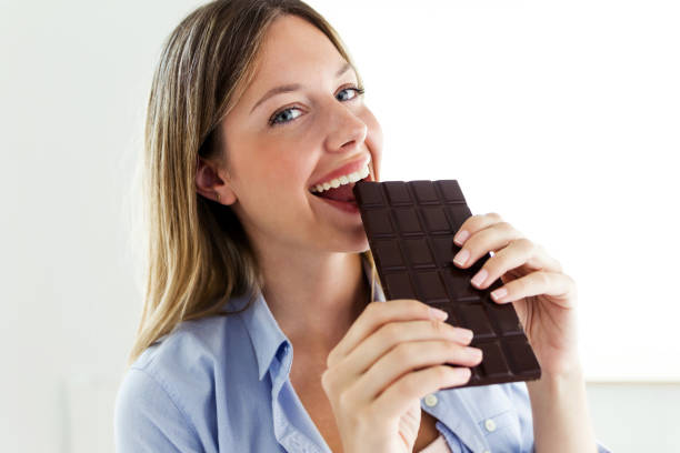 istock Beautiful young woman biting chocolate bar at home. 1040619212