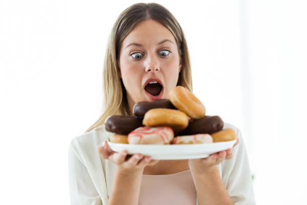 istock Surprised young woman looking donuts over white background. 1040619480