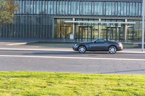 ESSEN, NRW, GERMANY - OCTOBER 11, 2015:
Chrysler Crossfire, side view of the new administrative building of ThyssenKrupp in Essen, Germany.