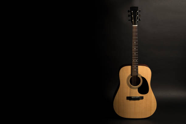 istock Acoustic guitar on a black background on the right side of the frame. Stringed instrument. Horizontal frame. 1040644190