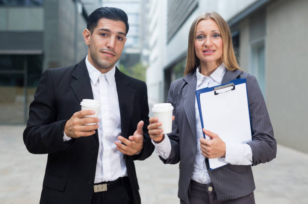 empresario y su colega de la mujer en traje de pie con carpeta y café - success signing businesswoman serious fotografías e imágenes de stock