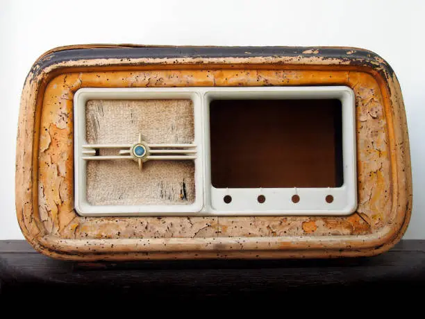 An old broken wooden vintage radio receiver with a cracked brown case and missing parts