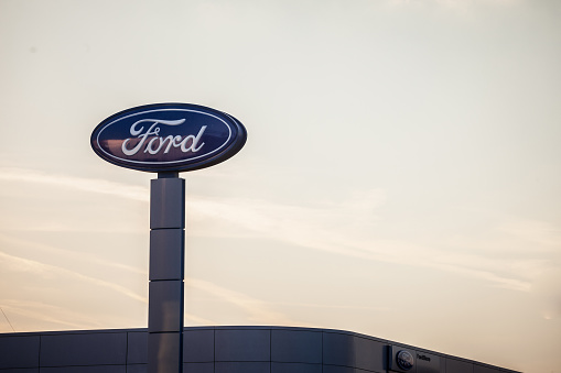 Picture of the Ford sign with their logo on their car dealership in New Belgrade, taken at sunset. Ford Motor Company is an American multinational automaker selling automobiles and commercial vehicles