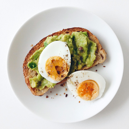 Avocado toast with hard boiled eggs on a white background, healthy breakfast, top view close up