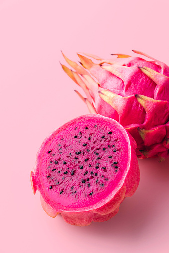 Fresh organic red dragon fruits on a pink background