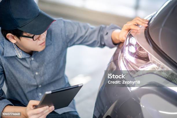 Young Asian Auto Mechanic Holding Digital Tablet Checking Headlight In Auto Service Garage Mechanical Maintenance Engineer Working In Automotive Industry Automobile Servicing And Repair Concept Stock Photo - Download Image Now