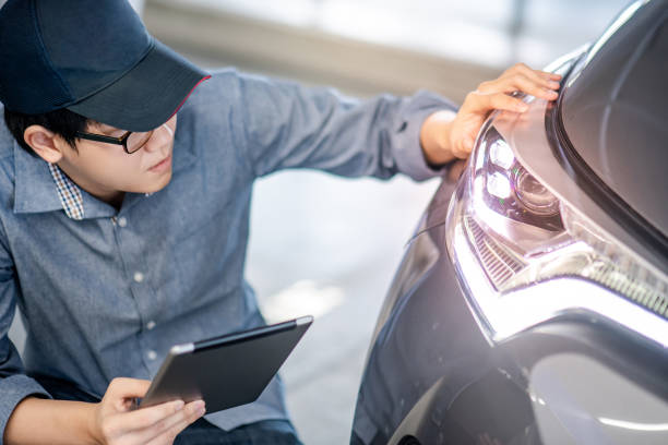 young asian auto mechanic holding digital tablet checking headlight in auto service garage. mechanical maintenance engineer working in automotive industry. automobile servicing and repair concept - automotive accessories imagens e fotografias de stock