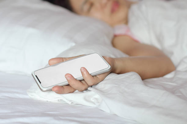 istock Woman sleeping in bed and holding a cell phone. 1040784978