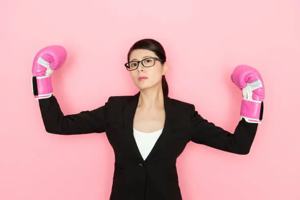 office lady showing the power with wearing the boxing gloves isolated on pink background