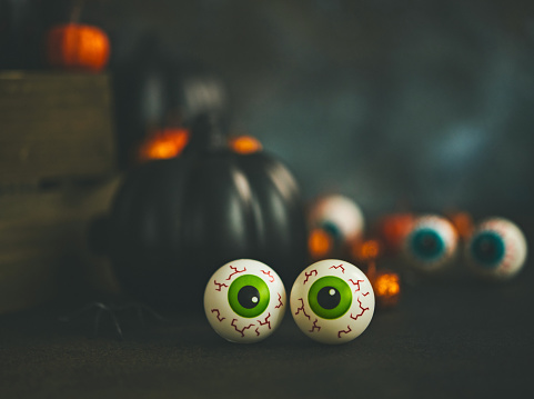 Halloween still life with orange and black glittery pumpkins, eyeballs and spiders